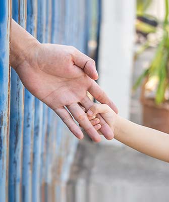 A person holding another persons hand over a fence